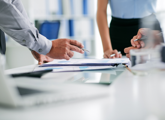 hand holding a pen, pointing at papers